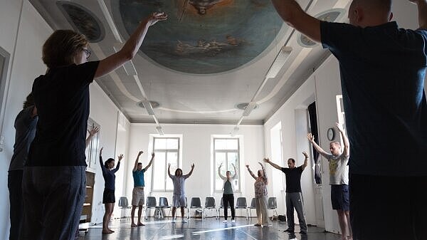 A group of people standing in a circle holding their hands up