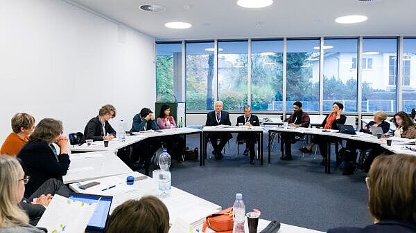 Conference room with a circular table and many people sitting and discussing