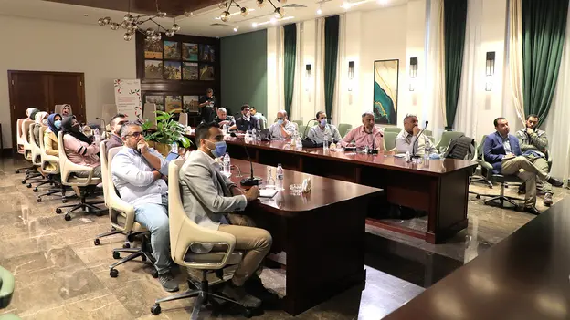 Training participants sitting at a u-shaped table listening to a speaker