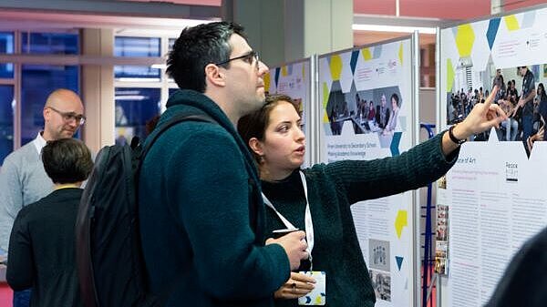 A woman explaining something to a man on a poster