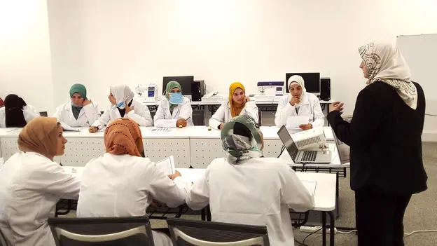A group of women sitting in a group at tables listening to a lecturer in front
