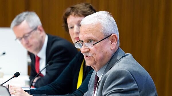 Two men and woman with microphones on their desk